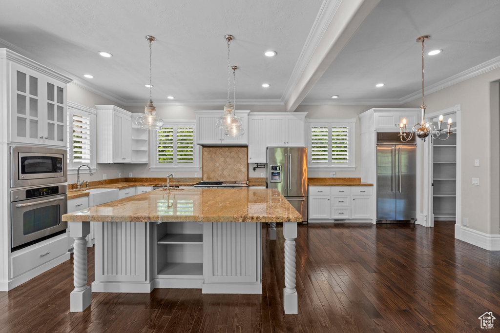 Kitchen with open shelves, built in appliances, healthy amount of natural light, a sink, and crown molding