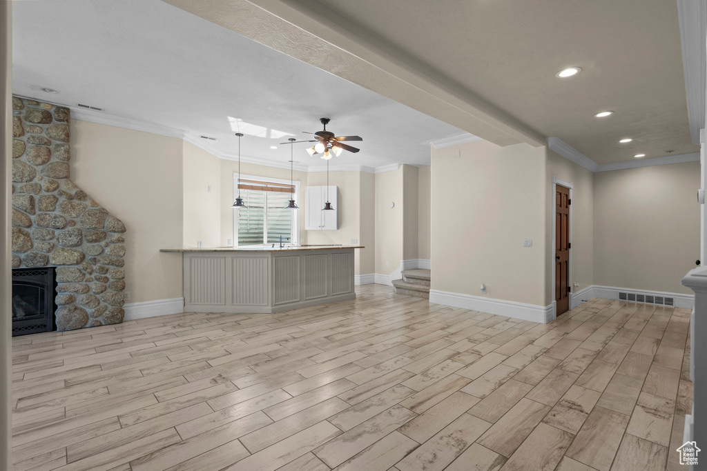 Unfurnished living room with crown molding, light wood-type flooring, baseboards, ceiling fan, and recessed lighting