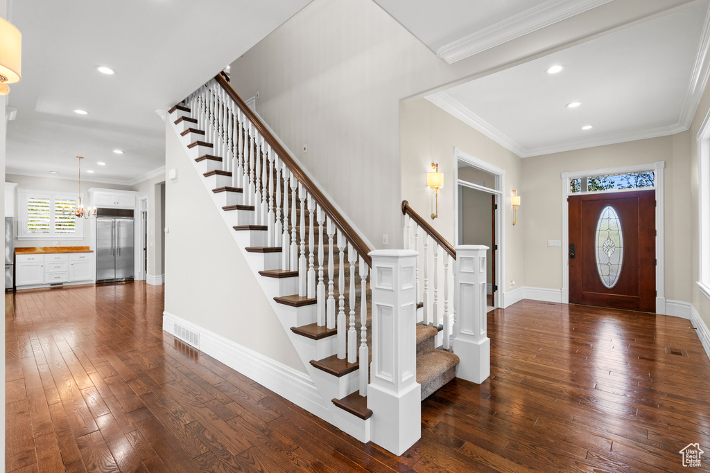 Entrance foyer featuring stairs, dark wood-type flooring, recessed lighting, baseboards, and ornamental molding