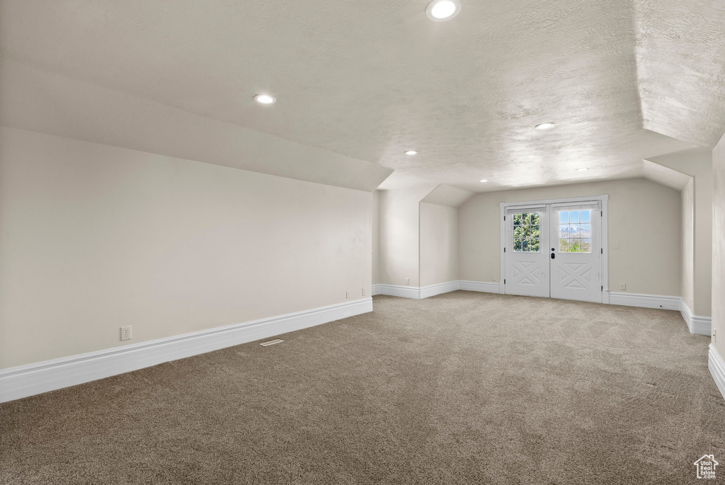 Bonus room with light colored carpet, recessed lighting, baseboards, a textured ceiling, and vaulted ceiling