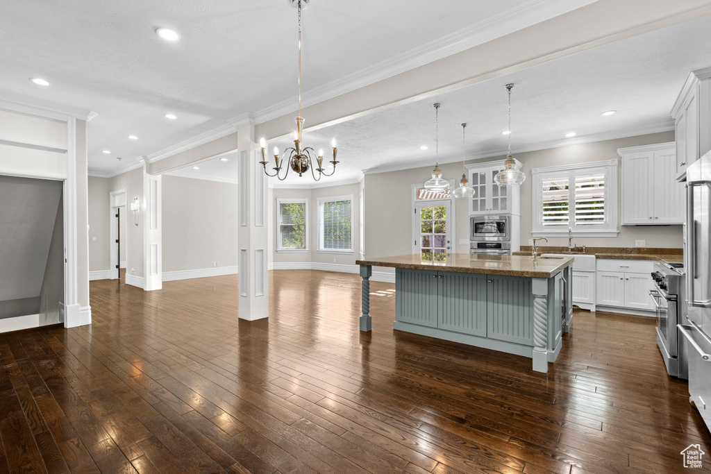 Kitchen with open floor plan, a center island with sink, stainless steel appliances, white cabinets, and a breakfast bar