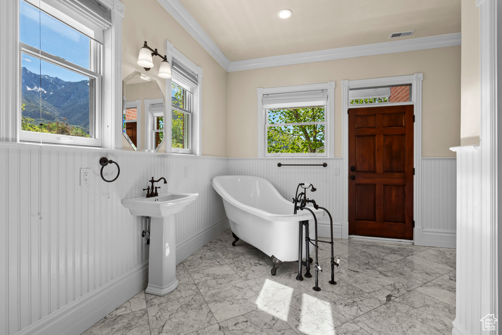 Full bath with wainscoting, marble finish floors, a freestanding tub, crown molding, and a mountain view