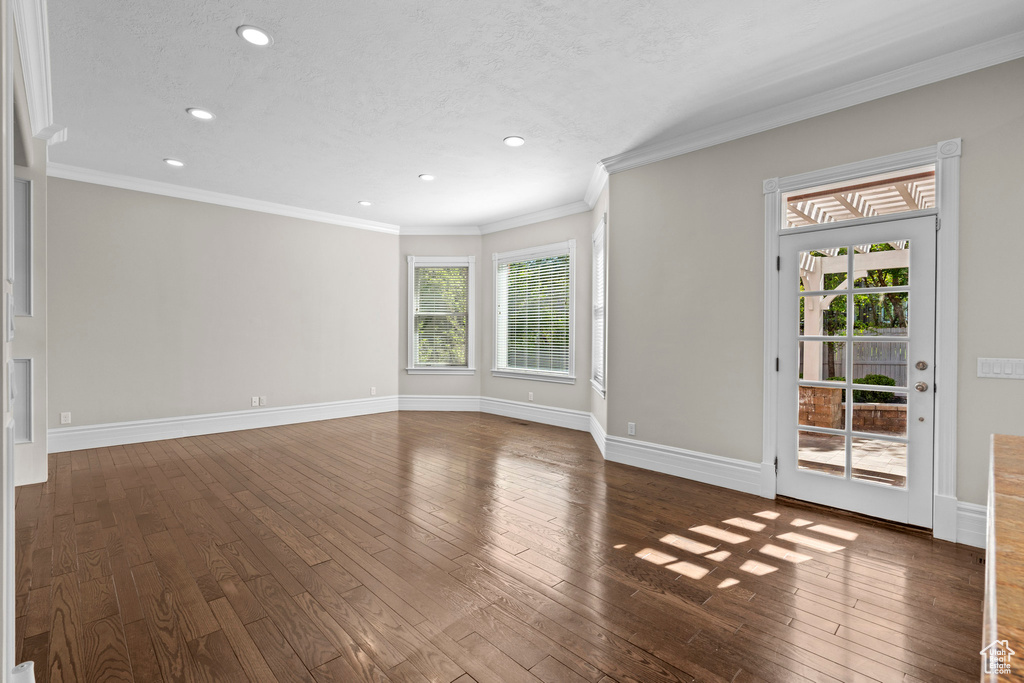 Unfurnished living room with recessed lighting, hardwood / wood-style floors, baseboards, ornamental molding, and a textured ceiling