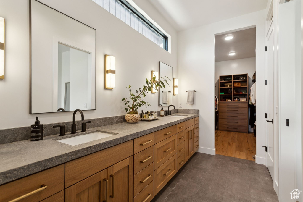 Bathroom with double vanity, a walk in closet, tile patterned flooring, and baseboards