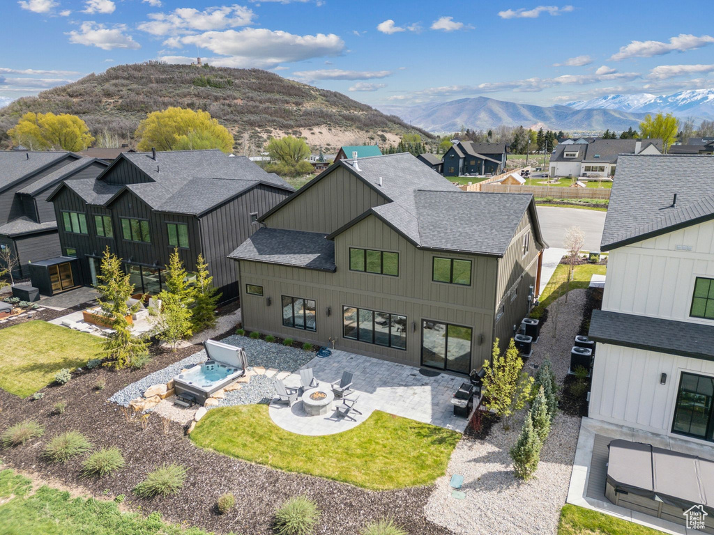 Back of property featuring roof with shingles, a mountain view, a patio, a residential view, and an outdoor fire pit