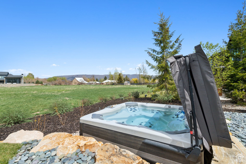 View of grassy yard featuring a hot tub and a mountain view