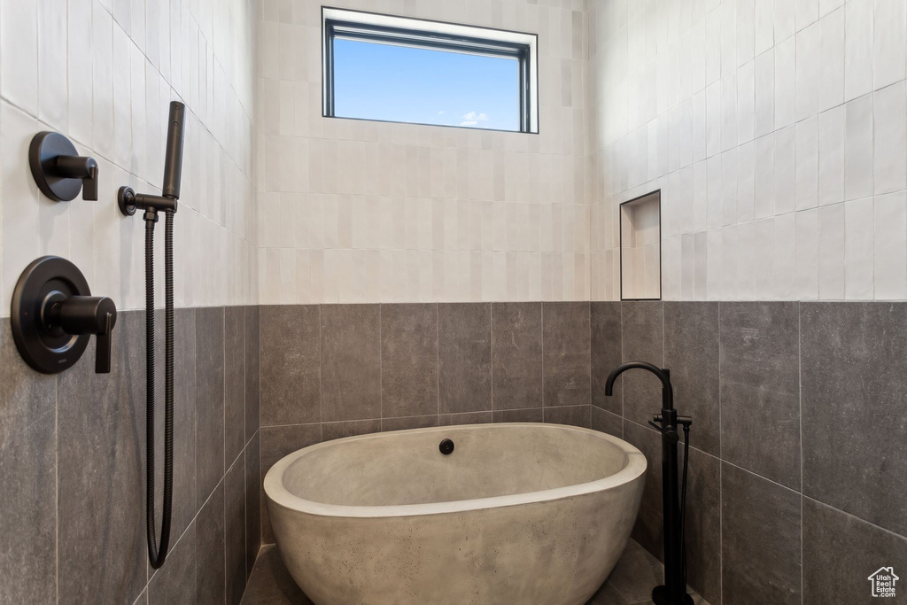 Full bathroom featuring tile walls, a freestanding bath, and a tile shower