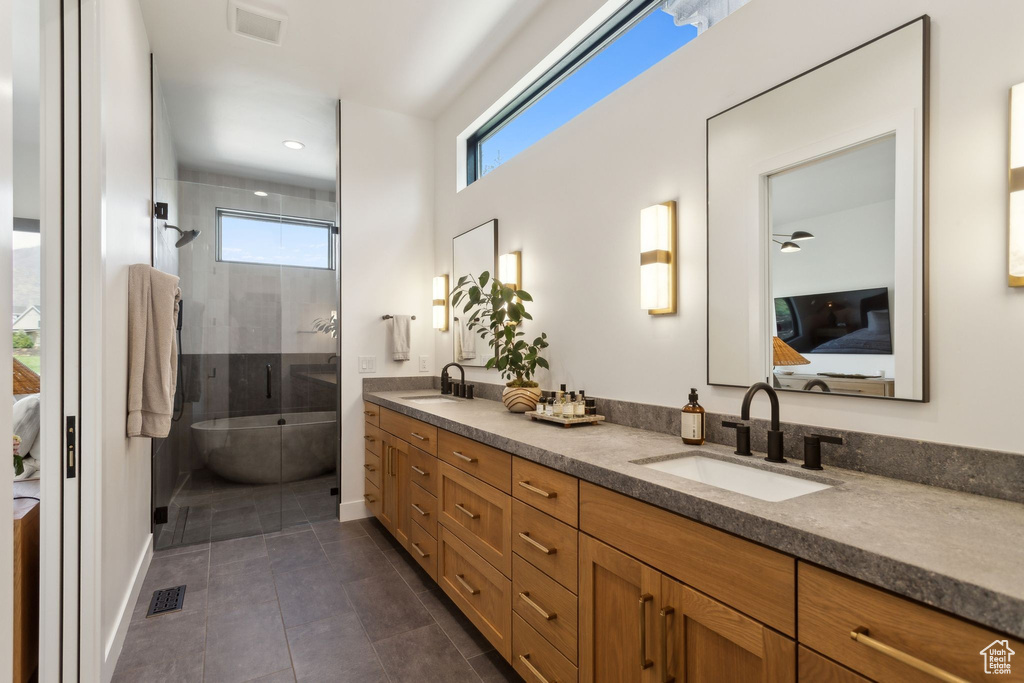 Ensuite bathroom with a stall shower, double vanity, a freestanding tub, baseboards, and tile patterned floors