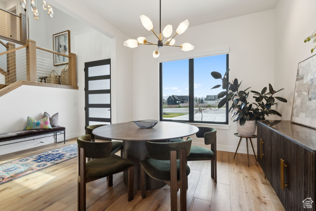 Dining area with a chandelier, light wood-type flooring, baseboards, and stairs
