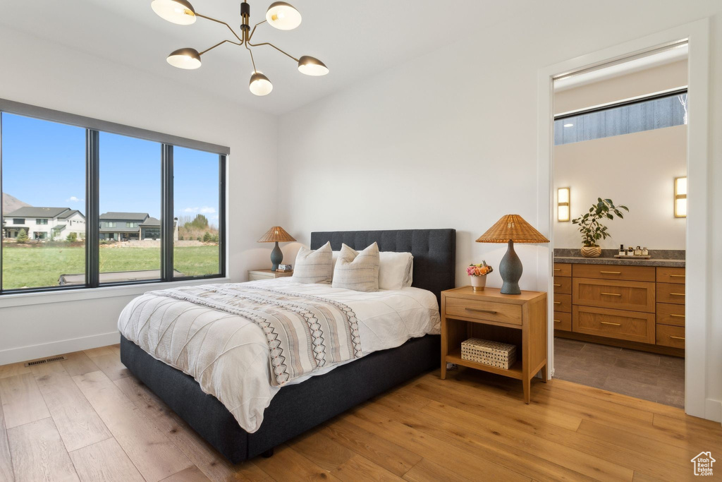 Bedroom with light wood-type flooring, a chandelier, and baseboards