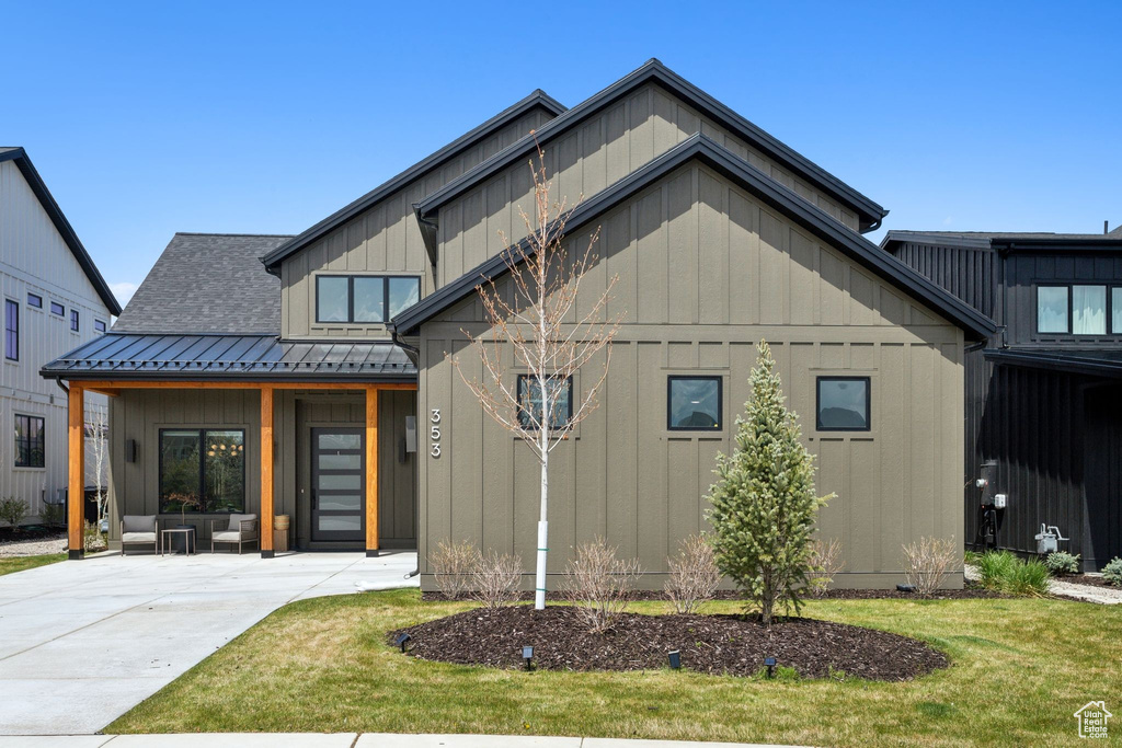 Modern inspired farmhouse featuring board and batten siding, a front yard, metal roof, and a standing seam roof