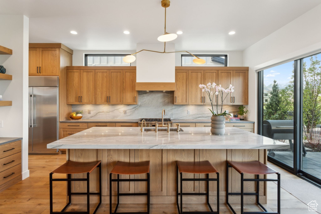 Kitchen featuring stainless steel built in refrigerator, decorative backsplash, a sink, open shelves, and recessed lighting