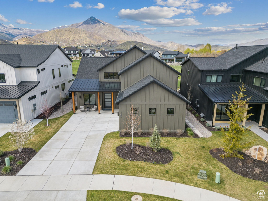 Modern farmhouse with board and batten siding, a mountain view, and a front yard