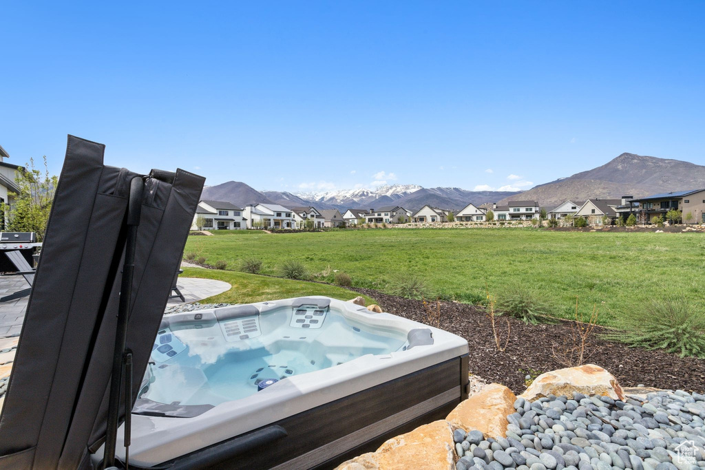 View of green lawn featuring a hot tub, a mountain view, and a residential view