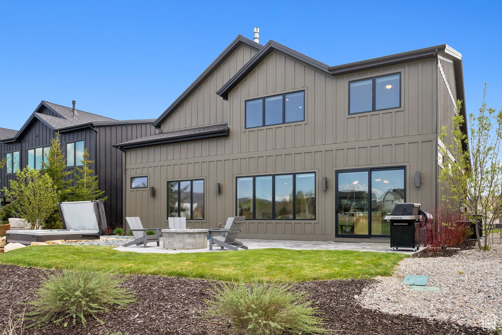 Back of property featuring board and batten siding, an outdoor fire pit, and a patio area