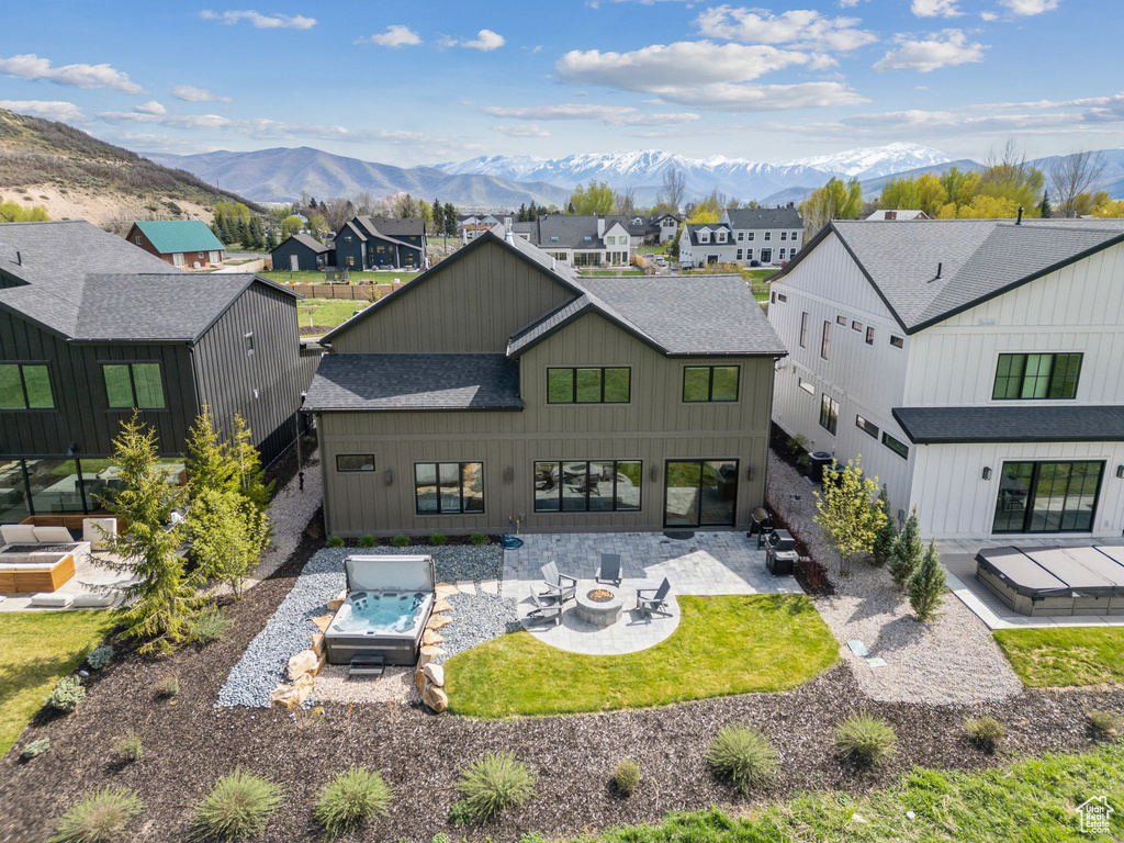 Rear view of property featuring roof with shingles, an outdoor fire pit, and a mountain view