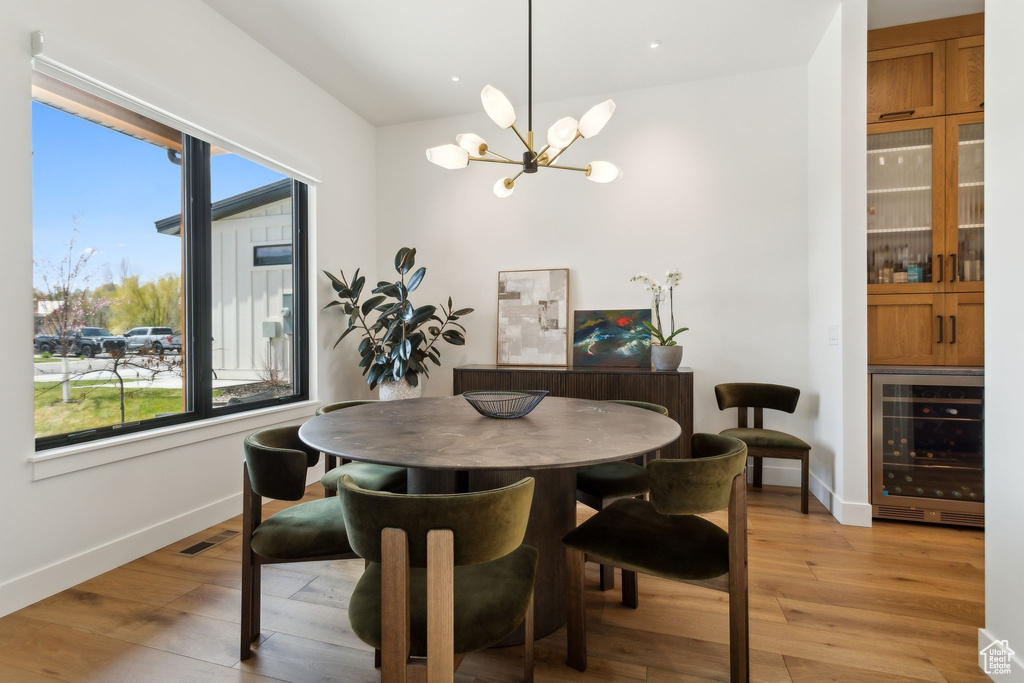 Dining area with beverage cooler, a chandelier, baseboards, and plenty of natural light