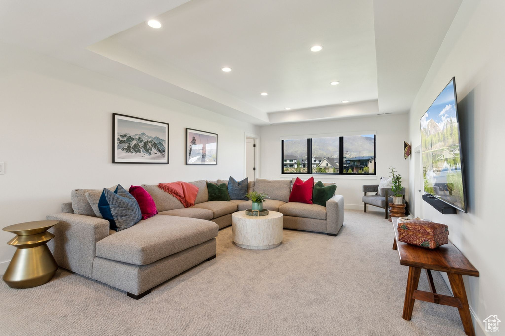 Carpeted living area with a tray ceiling, recessed lighting, and baseboards