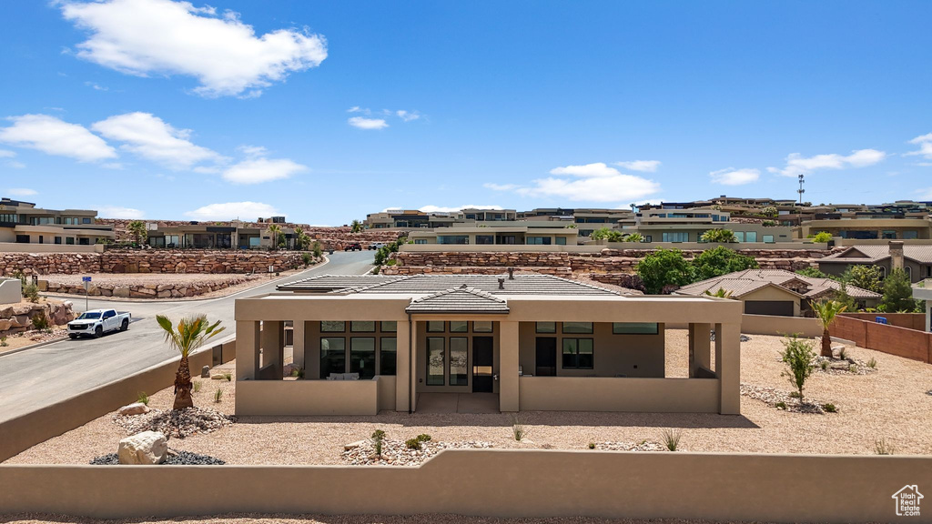 Back of house with stucco siding, fence, and a residential view