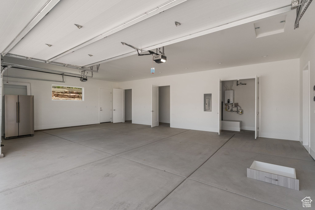 Garage with a garage door opener, freestanding refrigerator, and electric panel