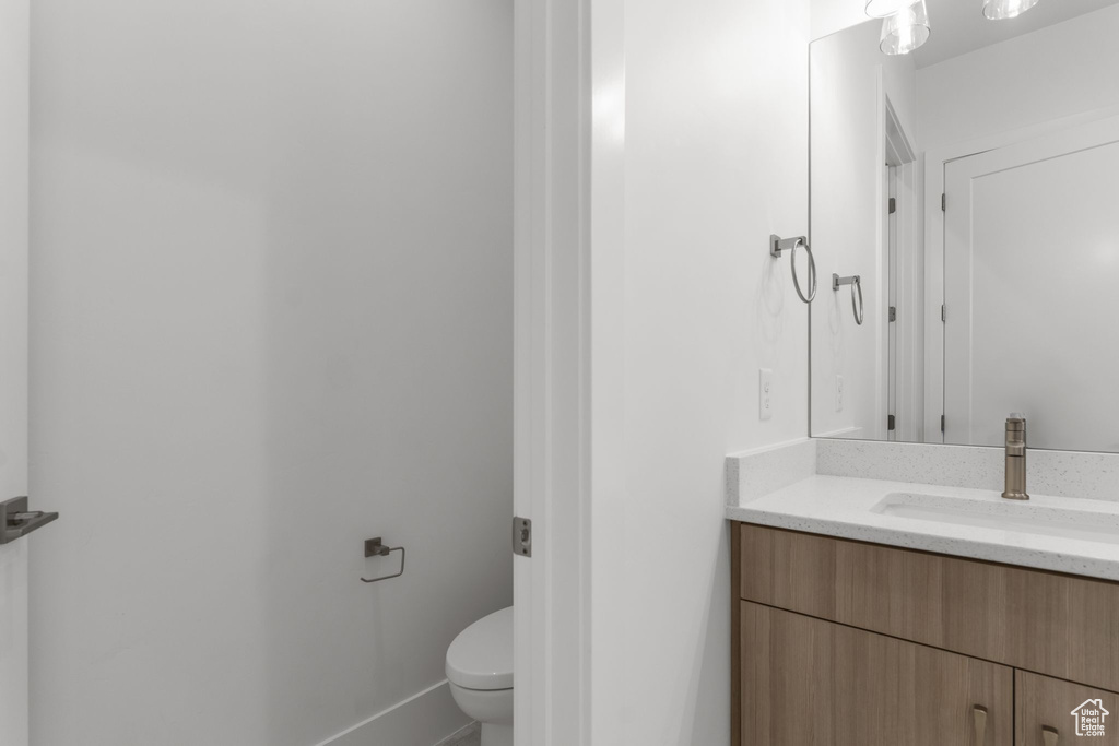 Bathroom with toilet, vanity, and baseboards