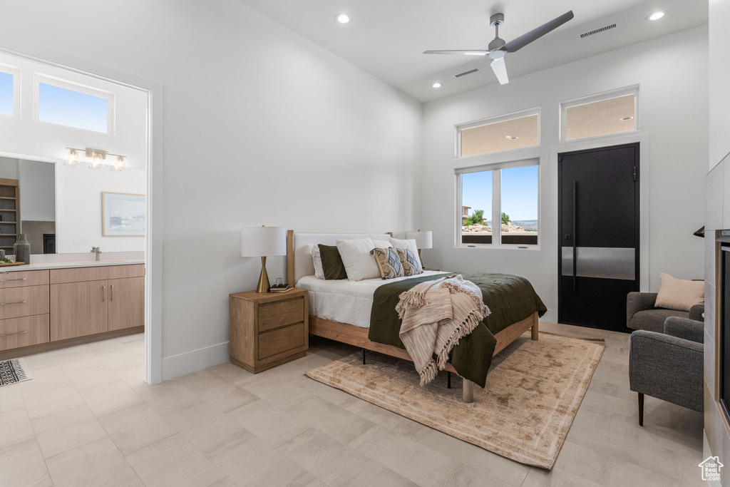 Bedroom with a towering ceiling, recessed lighting, ensuite bathroom, ceiling fan, and baseboards
