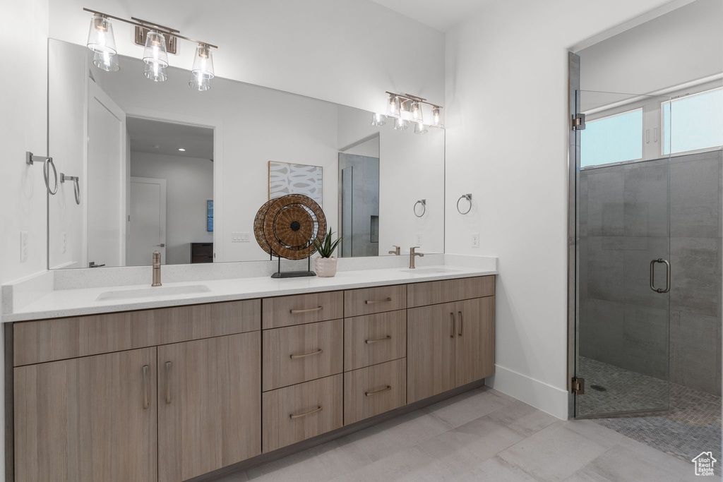 Full bath featuring double vanity, a shower stall, and baseboards