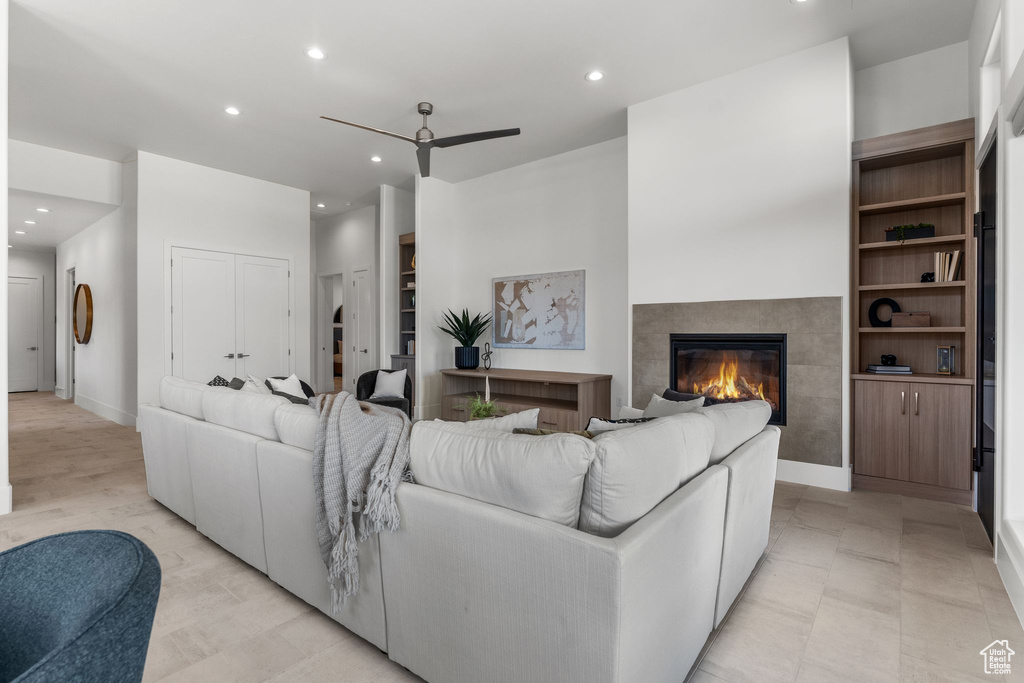 Living area with ceiling fan, recessed lighting, a tiled fireplace, built in shelves, and baseboards