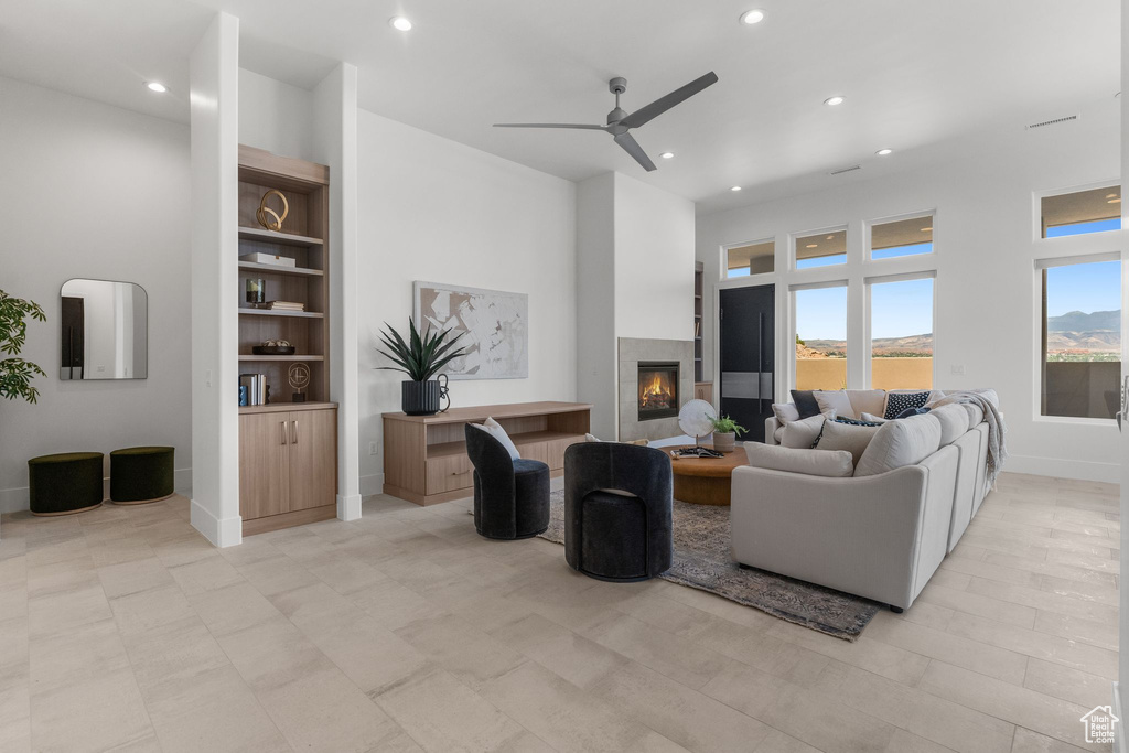 Living area featuring recessed lighting, a ceiling fan, a tile fireplace, baseboards, and built in shelves