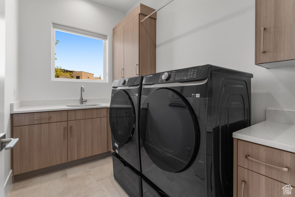 Clothes washing area featuring washing machine and dryer and cabinet space