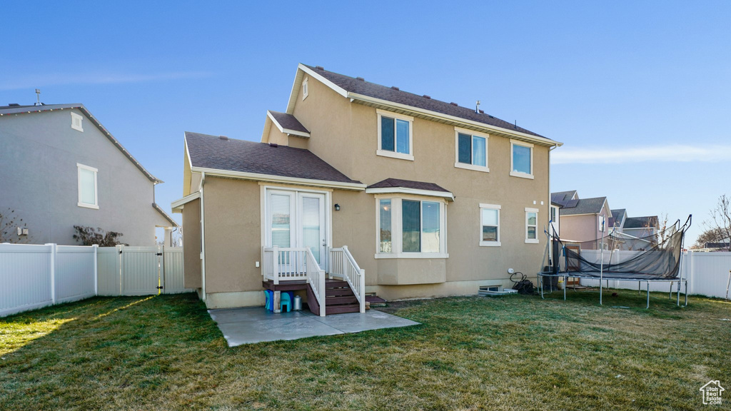 Rear view of house featuring a trampoline, stucco siding, and a gate