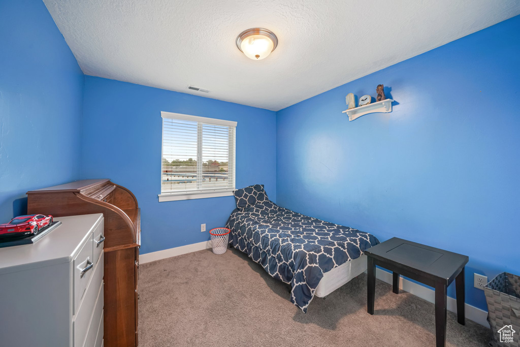 Carpeted bedroom featuring baseboards and a textured ceiling