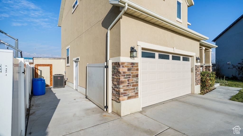 View of home's exterior featuring a gate, central air condition unit, a garage, and stucco siding