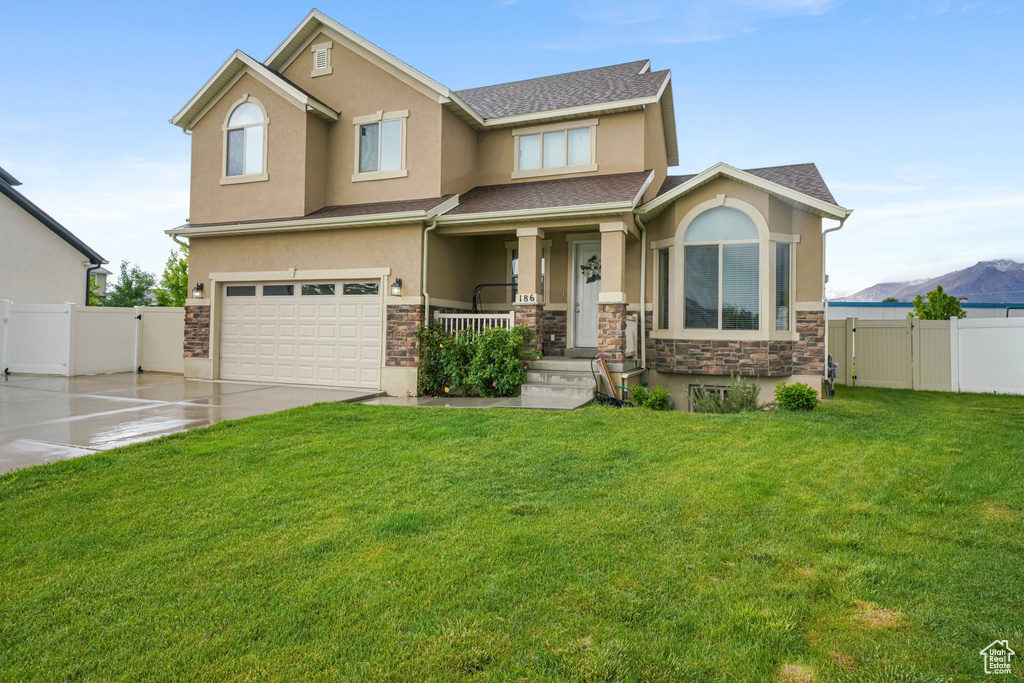 View of front facade featuring stone siding, stucco siding, an attached garage, covered porch, and driveway