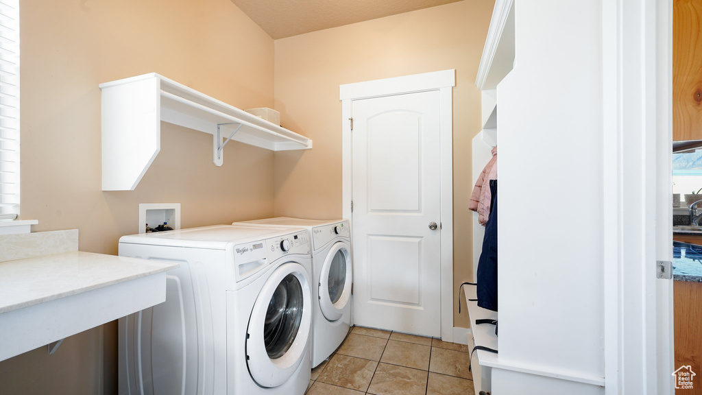 Washroom with separate washer and dryer and light tile patterned floors