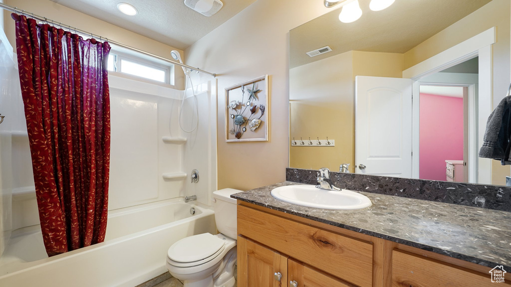 Full bathroom with toilet, shower / bath combo, and vanity