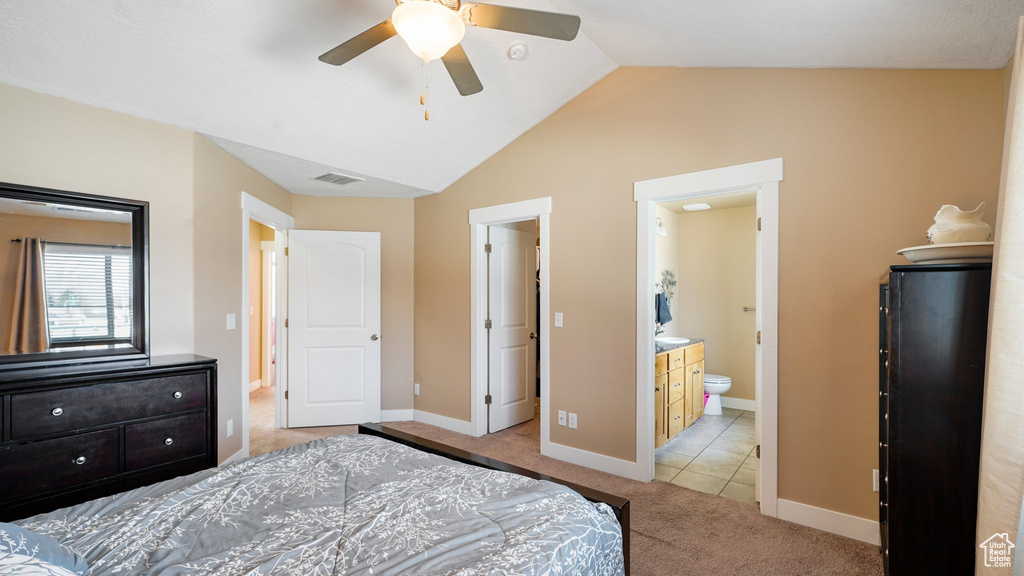 Bedroom with light colored carpet, lofted ceiling, baseboards, ensuite bathroom, and a ceiling fan