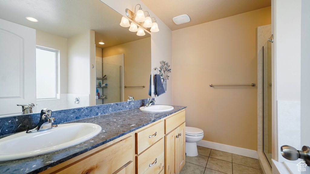 Full bath with a shower stall, tile patterned flooring, double vanity, toilet, and baseboards