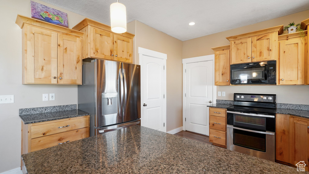 Kitchen with appliances with stainless steel finishes, light brown cabinets, baseboards, and recessed lighting
