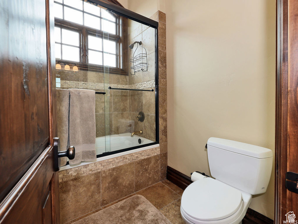 Bathroom with toilet, tiled shower / bath, and baseboards