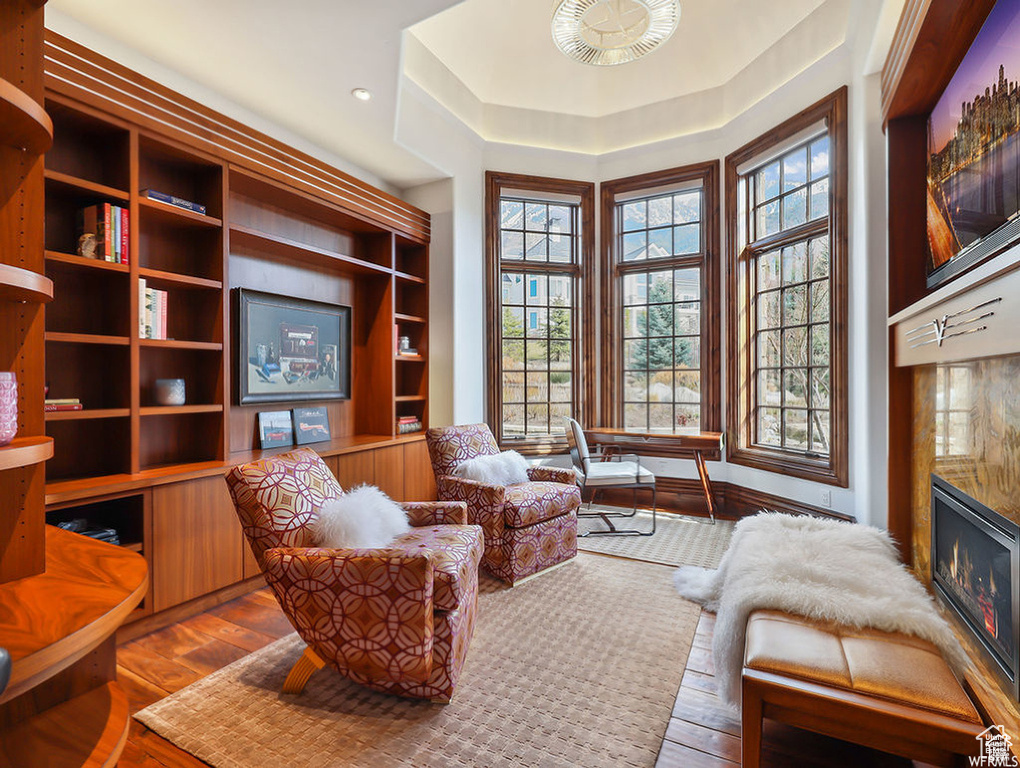 Living area with a high end fireplace, a healthy amount of sunlight, and wood-type flooring