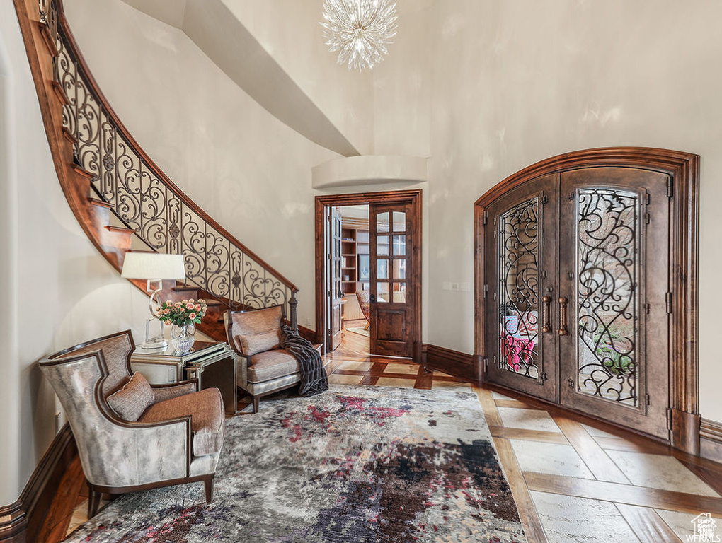 Entrance foyer with baseboards, a towering ceiling, stairway, arched walkways, and french doors