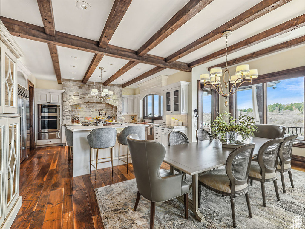 Dining space with dark wood-style flooring, a wealth of natural light, an inviting chandelier, and beamed ceiling