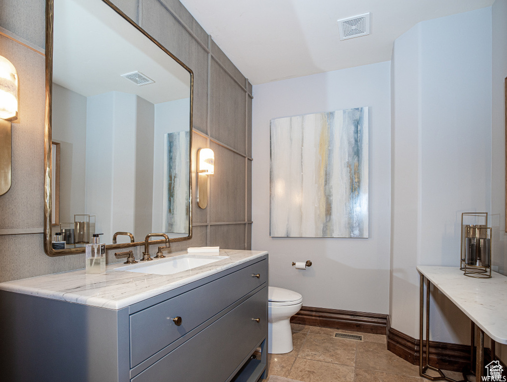 Bathroom featuring baseboards, visible vents, toilet, and vanity