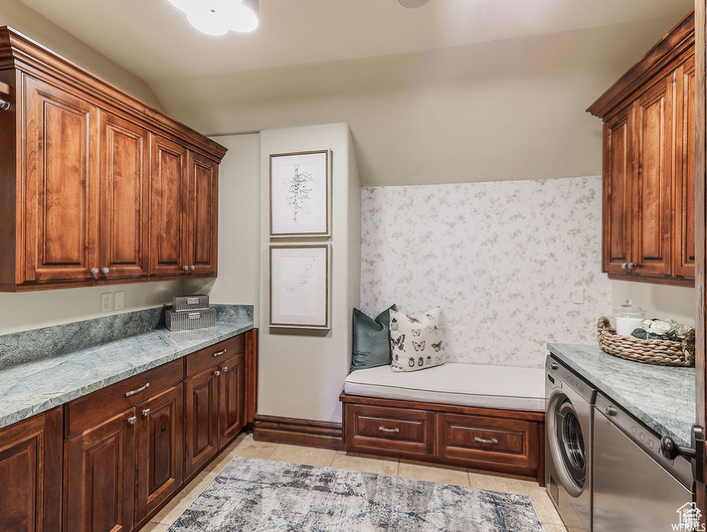 Clothes washing area featuring wallpapered walls, cabinet space, washer / dryer, and light tile patterned floors