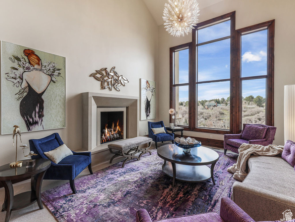 Living room with a lit fireplace, high vaulted ceiling, and a chandelier