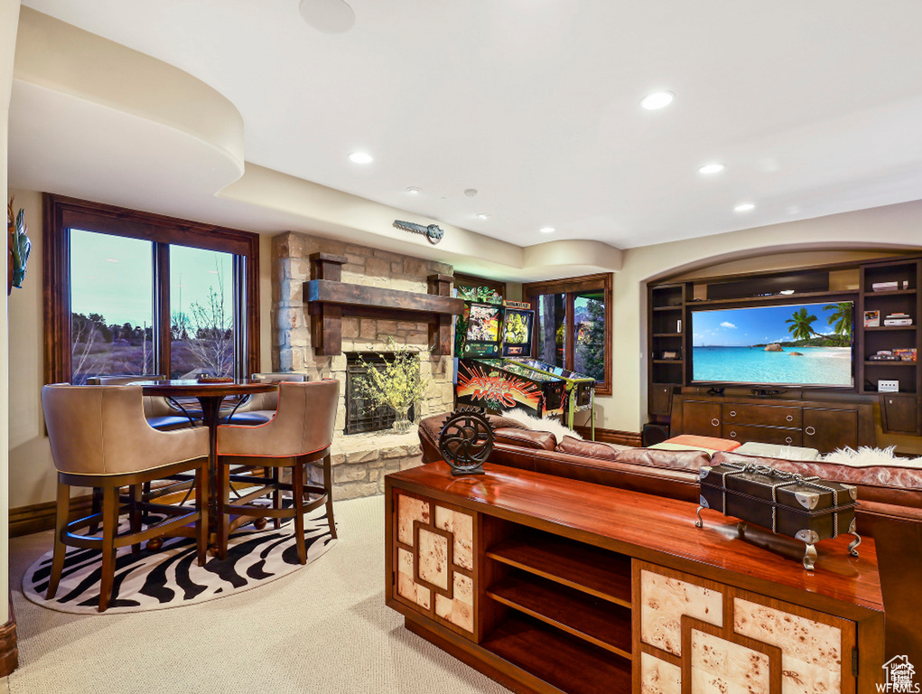 Living area featuring a stone fireplace, baseboards, recessed lighting, and carpet