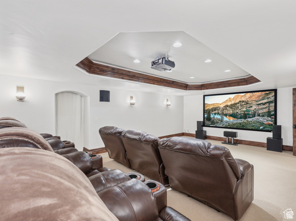 Home theater featuring a tray ceiling, crown molding, recessed lighting, baseboards, and carpet floors