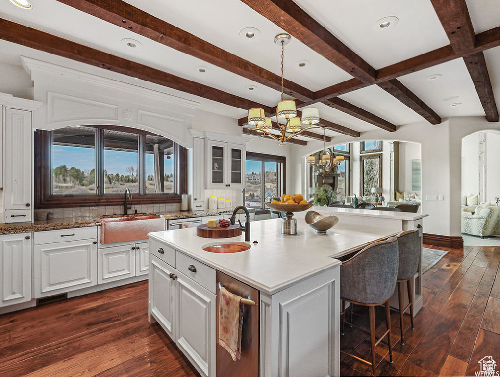 Kitchen with arched walkways, a sink, a notable chandelier, and open floor plan