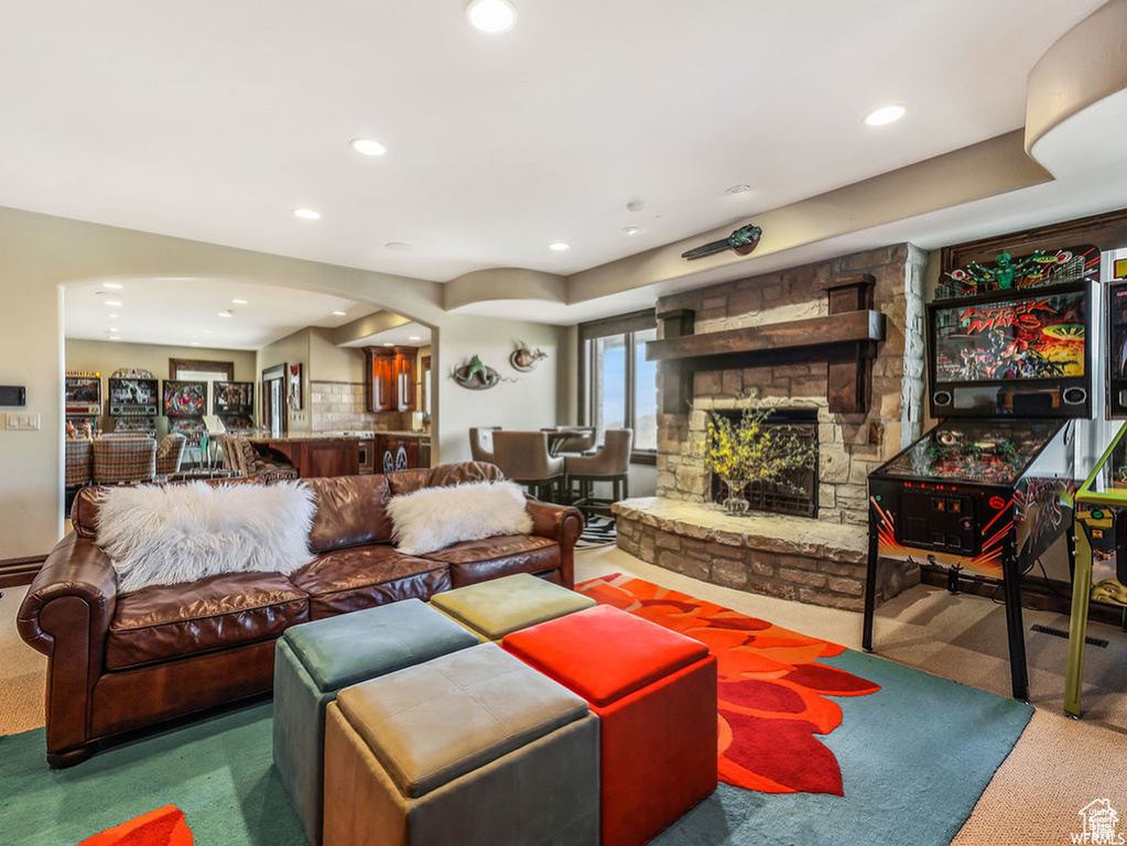 Carpeted living room with a stone fireplace, arched walkways, and recessed lighting